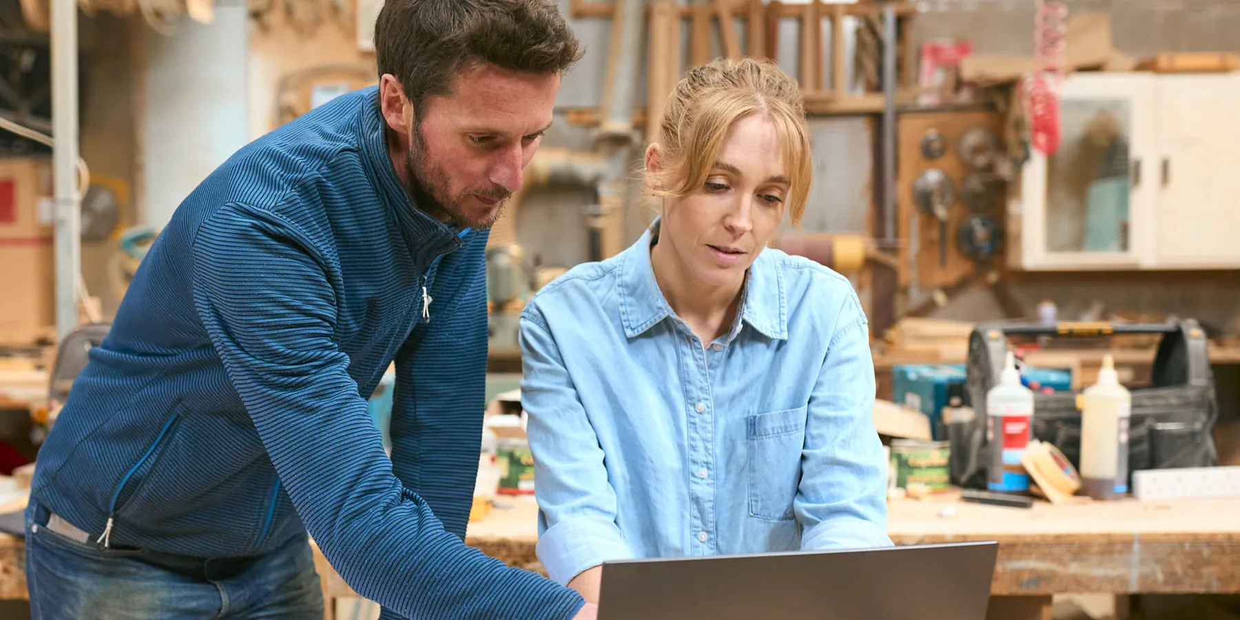 Two business owners talking over a laptop in a workshop