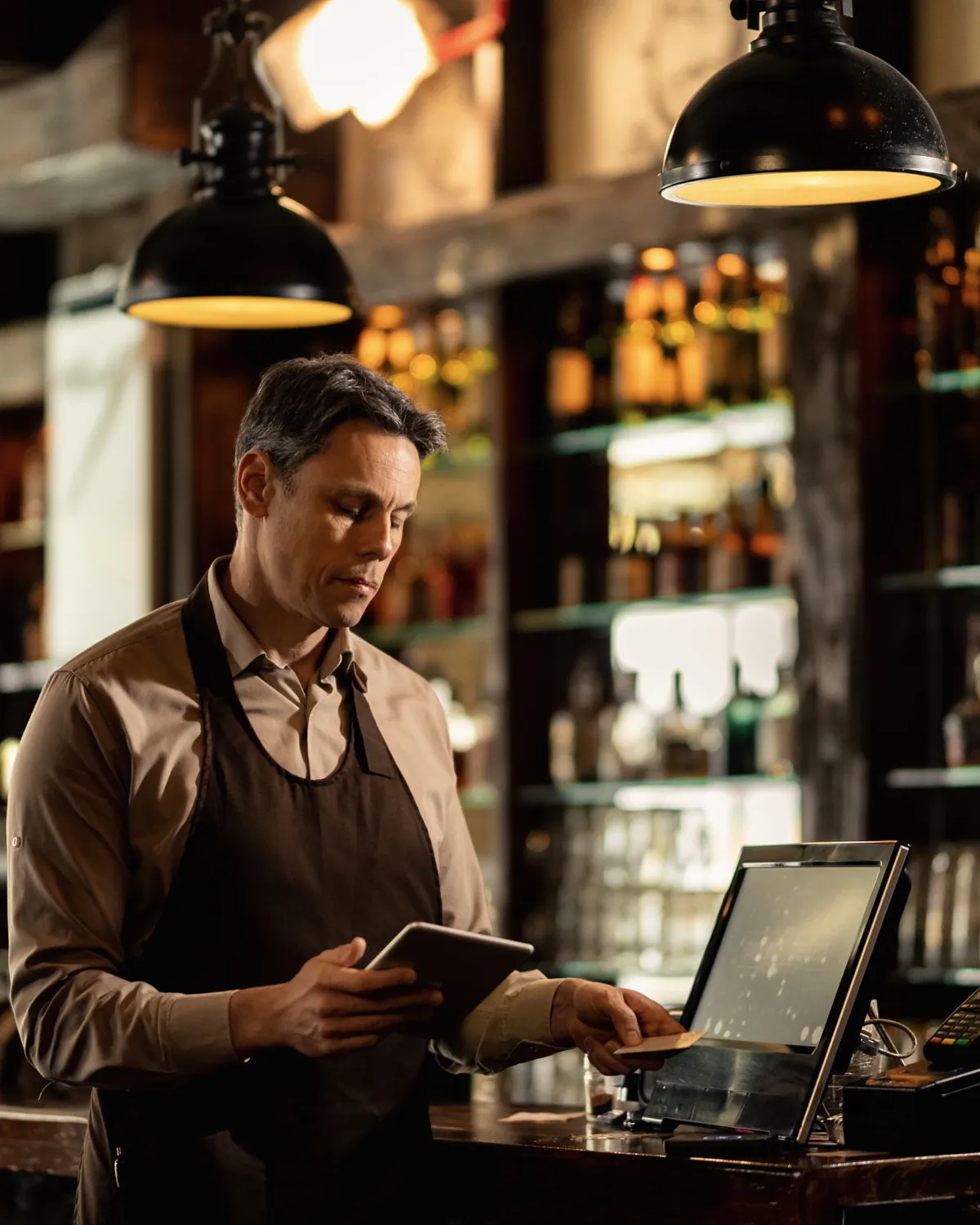 A small business owner reviewing the day's numbers on a tablet behind the counter