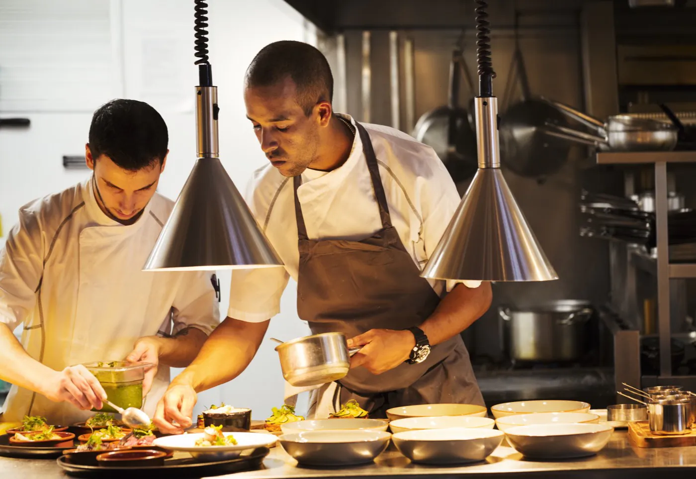 Chefs plating dishes on a busy restaurant pass
