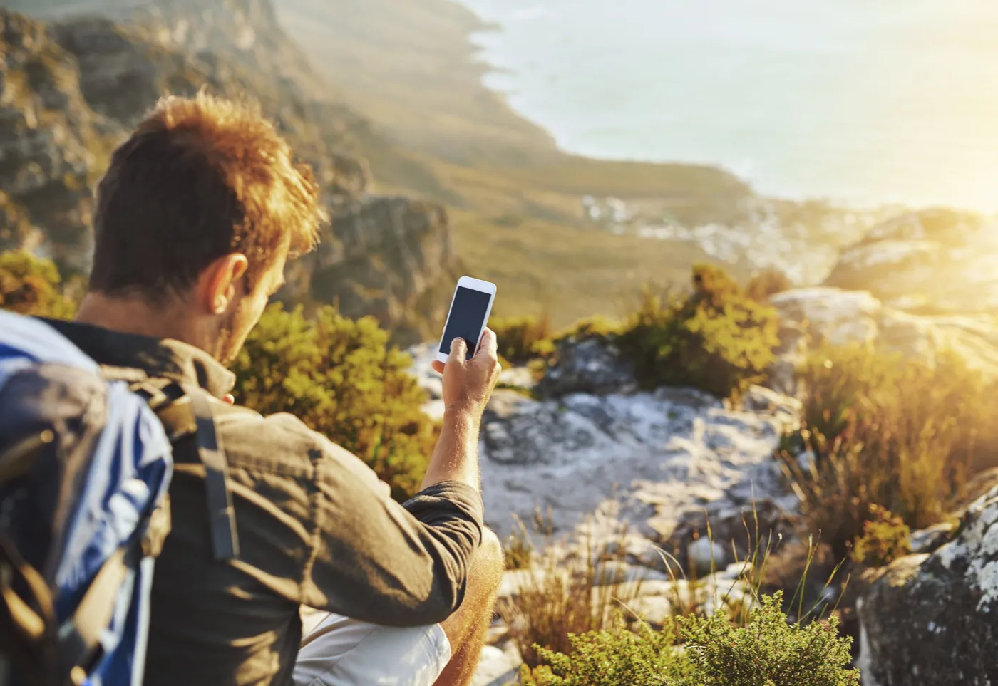 A traveller checking an itinerary on a phone at a coastal viewpoint